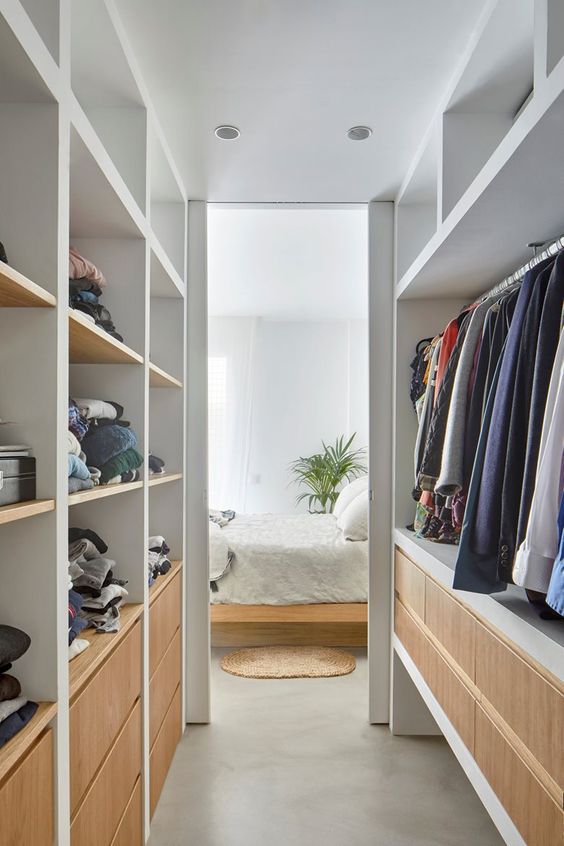 a narrow walk in closet with open storage compartments and drawers is a lovely space with built in lights