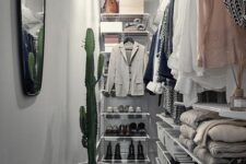 a narrow walk-in closet with white airy shelves and baskets for storage, railing and drawers, a mirror and a potted cactus