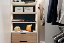 a narrow white closet with lit up open storage compartments, railing and a built-in dresser is a stylish and cool space