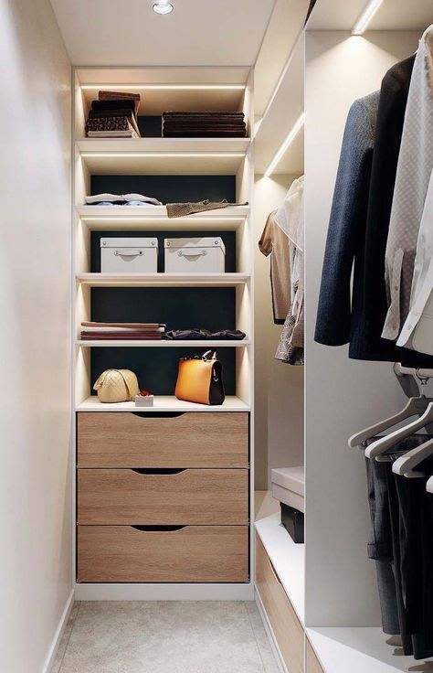 a narrow white closet with lit up open storage compartments, railing and a built in dresser is a stylish and cool space
