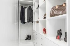a narrow white walk-in closet with railing, open storage compartments, drawers and some clothes and shoes