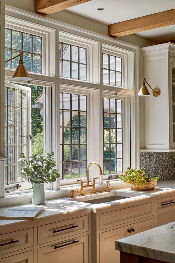 a neutral English country kitchen with a stylish casement window with French paning and brass wall lamps