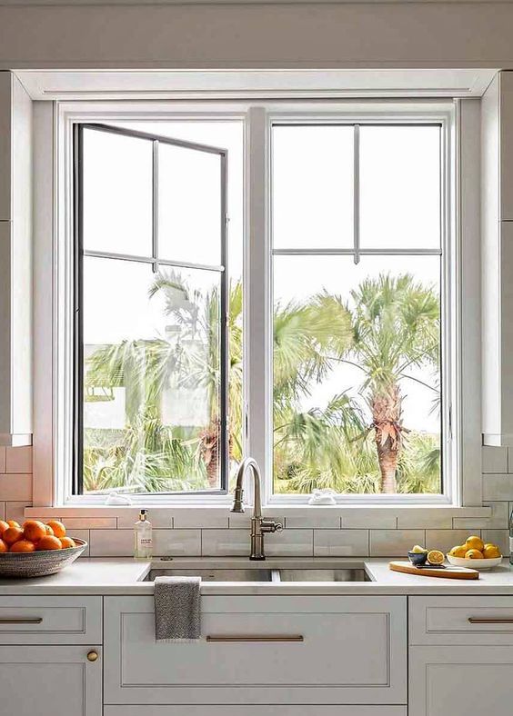 a neutral farmhouse kitchen with a cool casement window for a lovely view, shaker style cabinets and a white stone countertop