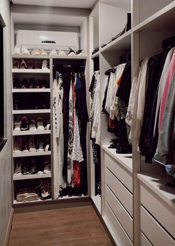 a neutral walk in closet with open storage compartments, drawers and shelves plus railings is a cool space to store your shoes and clothes