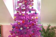 a purple Christmas tree decorated with bold ornaments and topped with a colorful tree topper is awesome