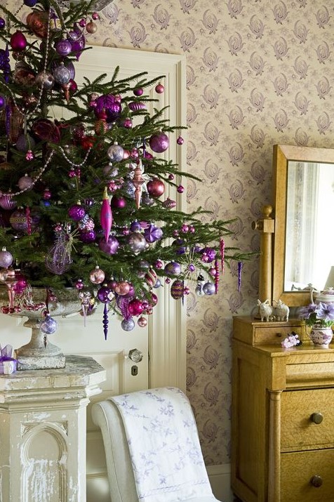 a small Christmas tree in a vintage urn, with fuchsia, purple and silver Christmas ornaments and beads, lights and icicles