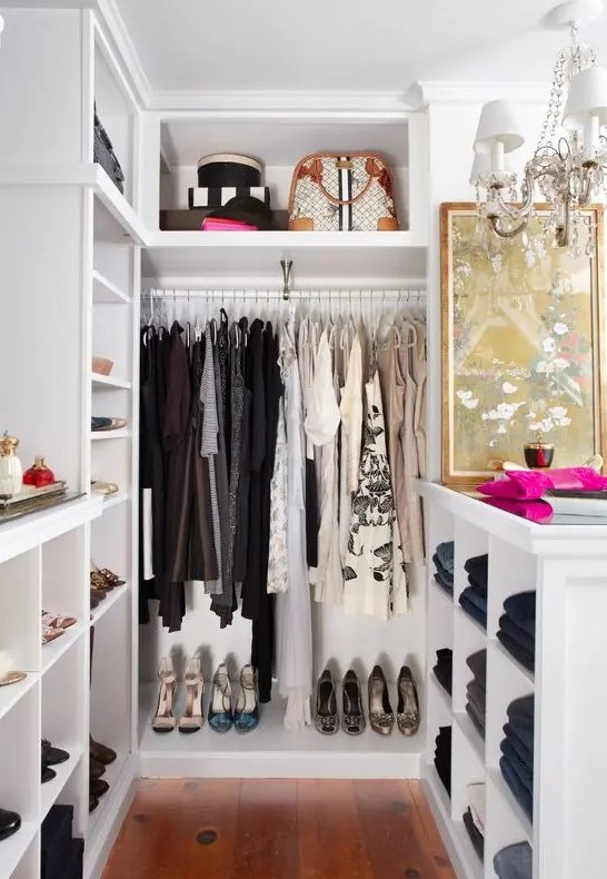 a small and glam closet in white, with built in shelves and wardrobes, with an open storage cabinet and a glam crystal chandelier