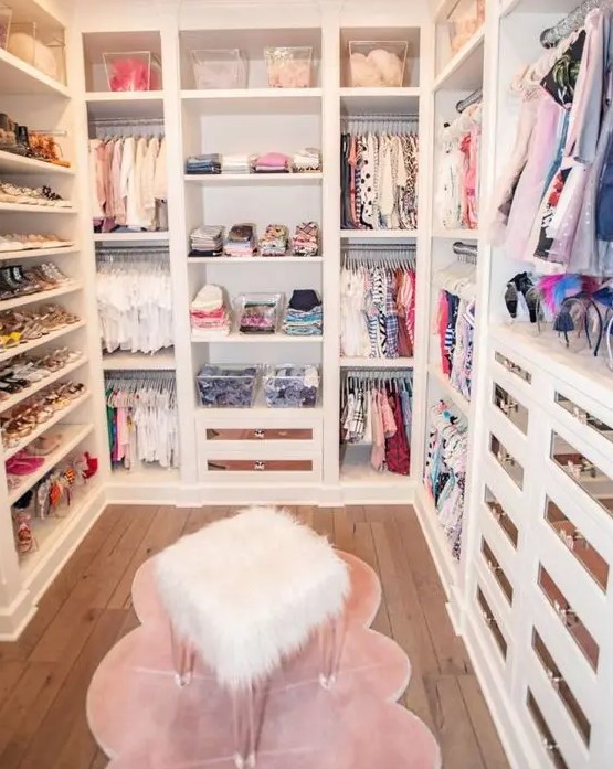 a small and glam closet with open shelves and storage units, drawers with mirror fronts, a pink rug and a faux fur stool is cool