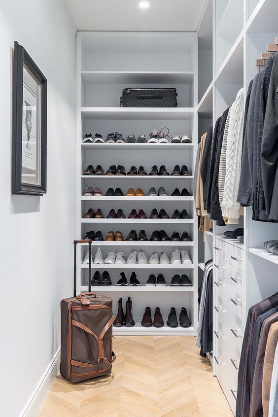 a small and narrow walk-in closet with open shelving and storage compartments, drawers and an artwork is a great space