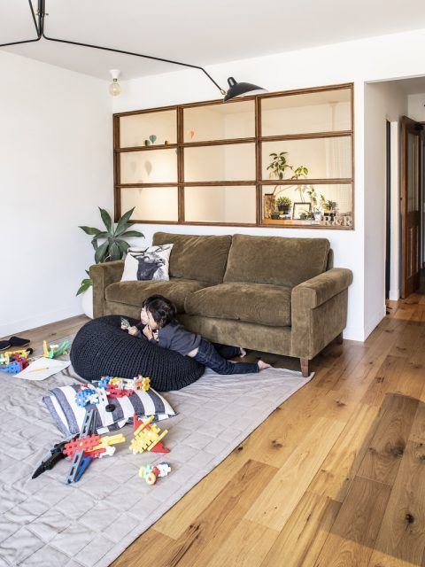 a small bedroom without any windows gets a lot of natural light from the living room through a large stained frame window