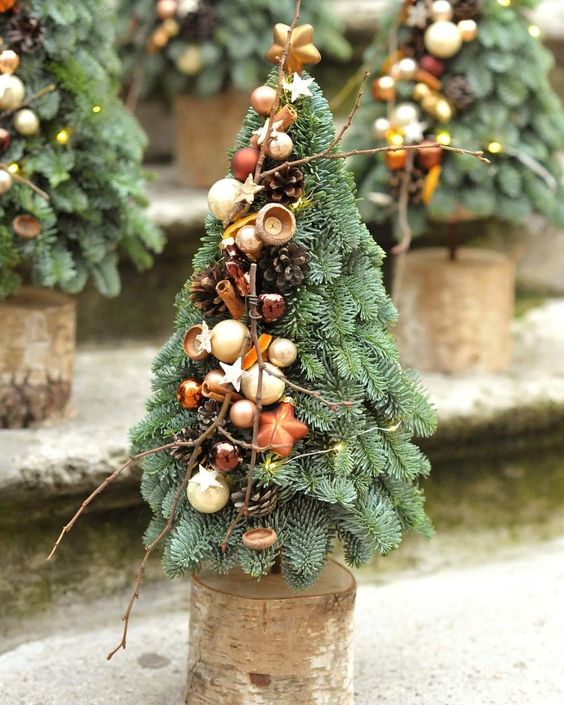 a small cone-shaped Christmas tree decorated with twigs, beads, stars, small pinecones and nuts for a rustic space