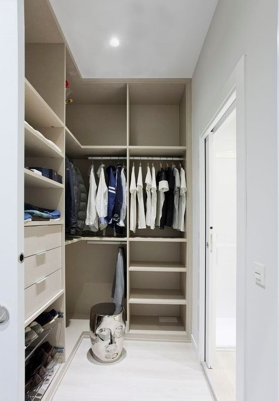 a small minimalist closet with lots of open storage space, dome drawers and holders for hangers, a creative stool and a glass sliding door