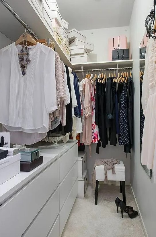 a small neutral closet with an L-shaped shelf for boxes and a rack under it to hang stuff, a couple of IKEA dressers