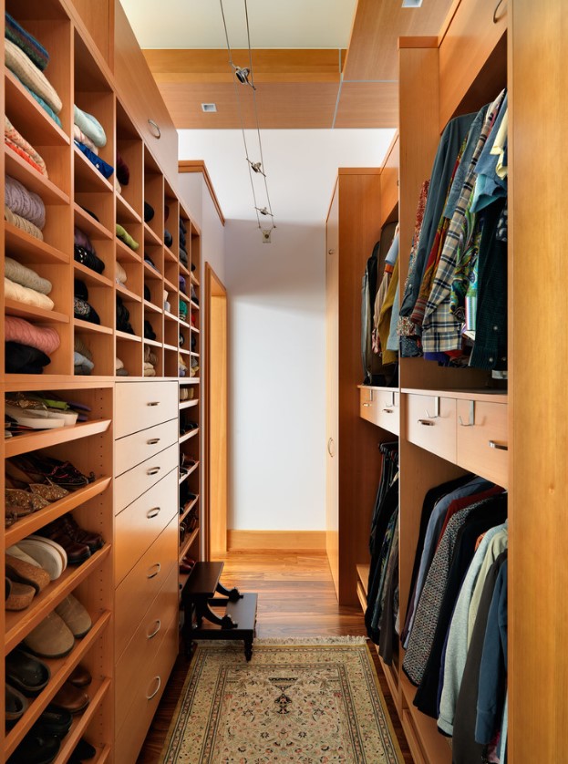 a stained narrow walk-in closet with lots of shelves, drawers and even steps to reach all the necessary things