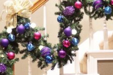 a staircase garland with blue, purple and fuchsia ornaments and large neutral bows and lights is amazing for a bright touch