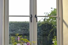 a stylish country space with a casement window, with a gorgeous view of the garden and some greenery and blooms around