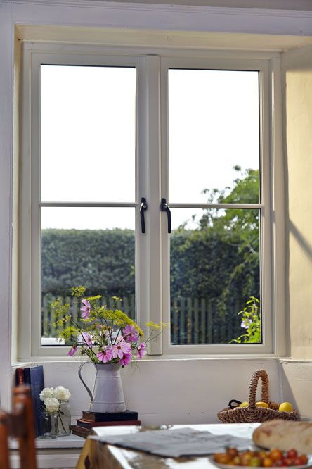 a stylish country space with a casement window, with a gorgeous view of the garden and some greenery and blooms around