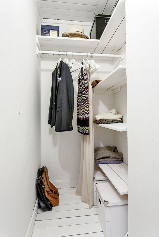 a tiny Scandinavian closet with built-in shelves, a rack with clothes hangers and some boxes for shoes is all cool
