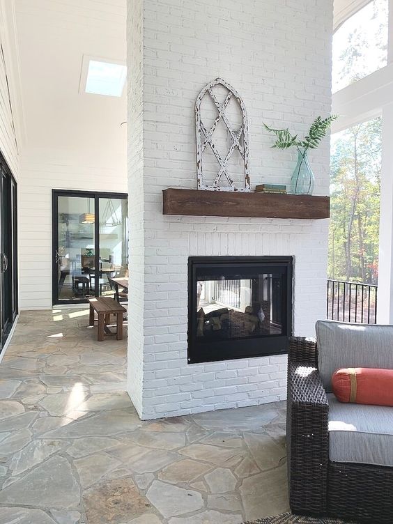 a white brick space divider with a built-in fireplace that can be seen from both the dining and living room