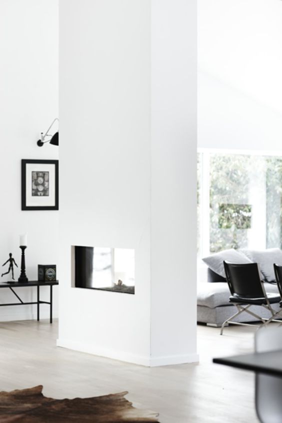 a white dual-sided fireplace separates the living room and entryway and gives coziness and a welcoming feeling to both