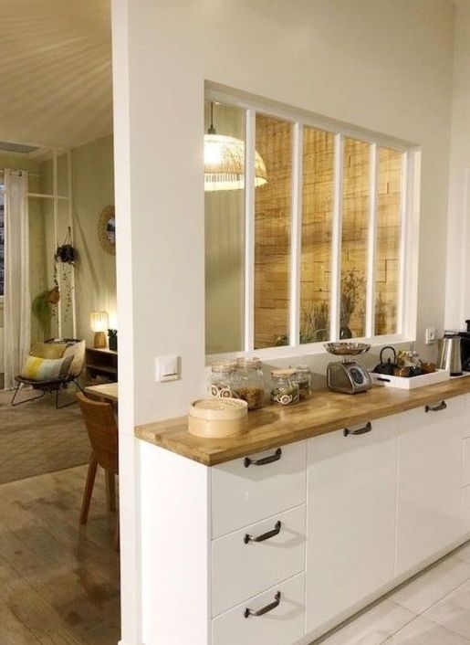 a window with white framing connects the living room and the kitchen allowing more natural light into both spaces