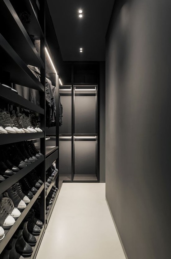 an ultra-minimalist black and graphite grey closet with lots of shoe shelves and some drawers plus holders for hangers