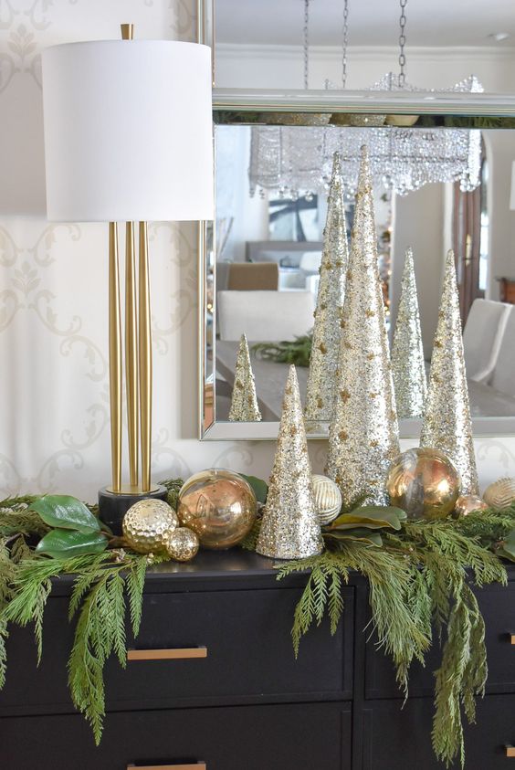 metallic cone-shaped tabletop Christmas trees paired with metlalic ornaments and evergreens are great console decor