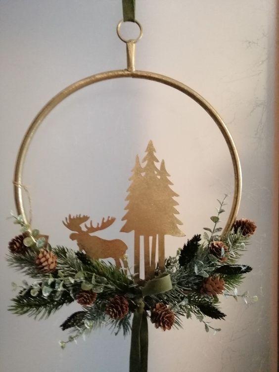 a beautiful embroidery hoop Christmas wreath of evergreens, pinecones, plywood trees and a moose plus a ribbon bow