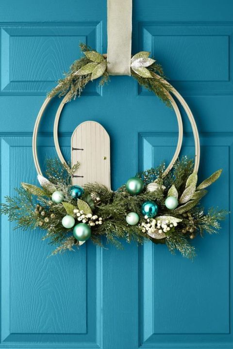 a bold double embroidery hoop Christmas wreath with greenery and foliage, pastel and blue ornaments, berries and a ribbon
