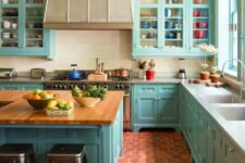 04 a bright blue kitchen with terracotta tile on the floor, a large vintage hood, butcher block countertops and a patterned ceiling
