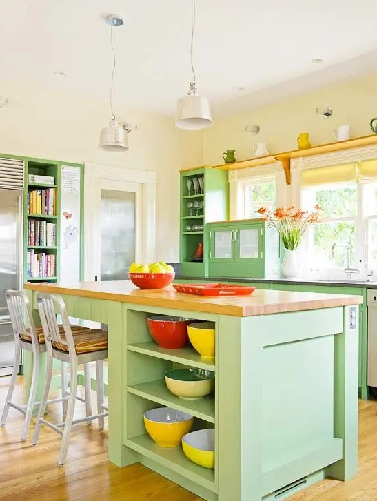 a colorful green kitchen with a matching kitchen island, butcherblock countertops, red and yellow accessories and touches