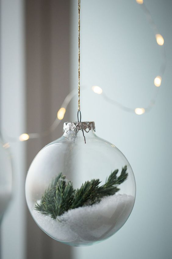 a clear glass Christmas ornament with faux snow and evergreens is a dreamy winter-inspired decor idea
