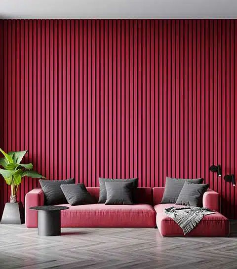 a gorgeous magenta living room with a pink low sofa, grey pillows, a potted plant and a side table is amazing