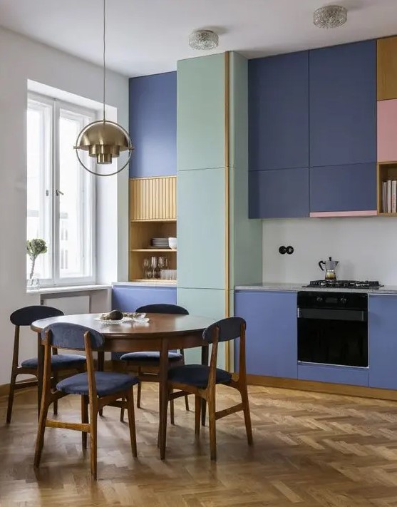 a contemporary kitchen with bold purple sleek cabinets, bright pink and yellow touches and purple chairs plus a gold pendant lamp