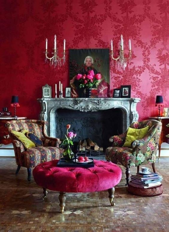 a lovely magenta vintage-inspired living room with a vintage fireplace, chic printed chairs and a hot pink ottoman, vintage artworks