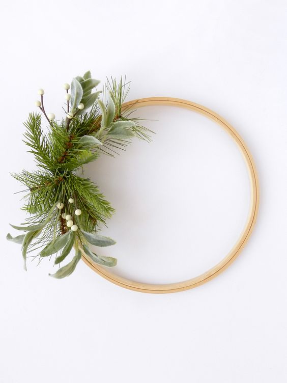 a minimalist Christmas wreath of an embroidery hoop with greenery, evergreens and white berries is a lovely decoration for the holidays