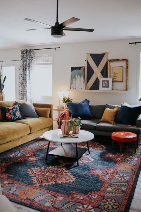 a bold mid-century modern space done with a printed rug, a couple of sofas and colorful pillows, a ledge gallery wall