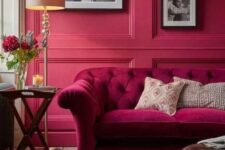 12 a magenta living room with a matching sofa, a leathe rottoman, some artworks and a side table plus a floor lamp