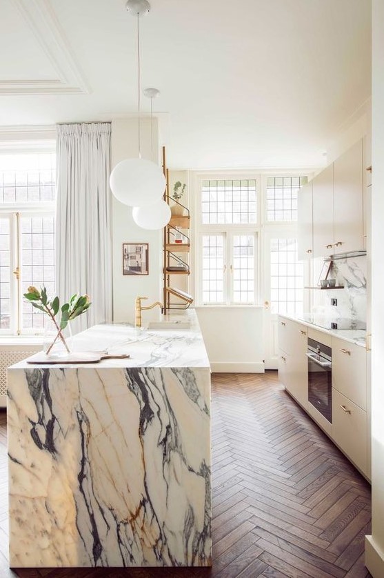 a chic modern kitchen in white and a white marble kitchen island, gold fixtures for a more glam look
