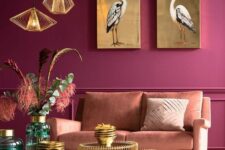 13 a magenta living room with molding, a salmon pink sofa, an arrangement of gold coffee tables, catchy pendant lamps and gold artworks