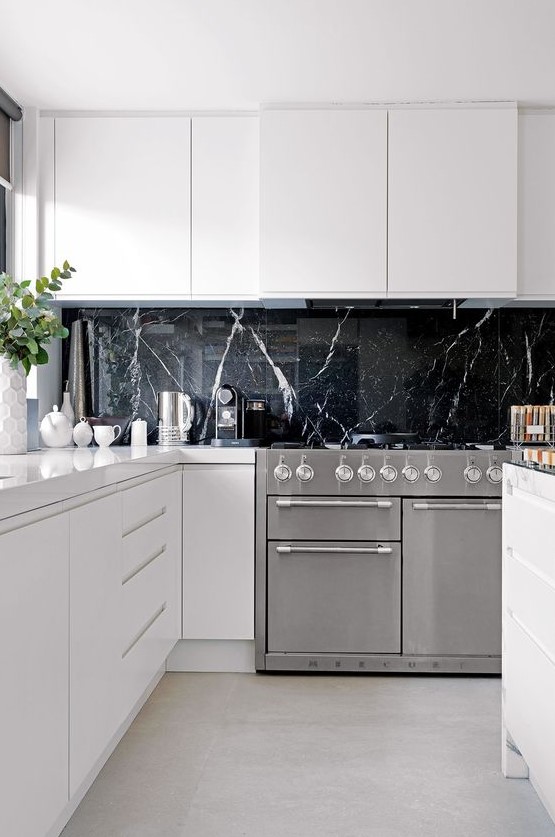 a black marble kitchen backsplash is a very luxurious touch to these ultra-minimalist white cabinets