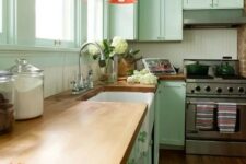 17 a pretty mint green kitchen with a white beadboard backsplash, butcherblock countertops, red pendant lamps and green knobs