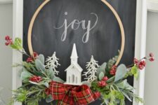 18 a small and cool embroidery hoop Christmas wreath with greenery, berries, a red plaid bow, a church and white faux trees