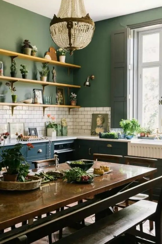 a stylish vintage kitchen with green walls, white subway tiles, teal cabinets, a dark stained dining set, a crystal chandelier and potted greenery