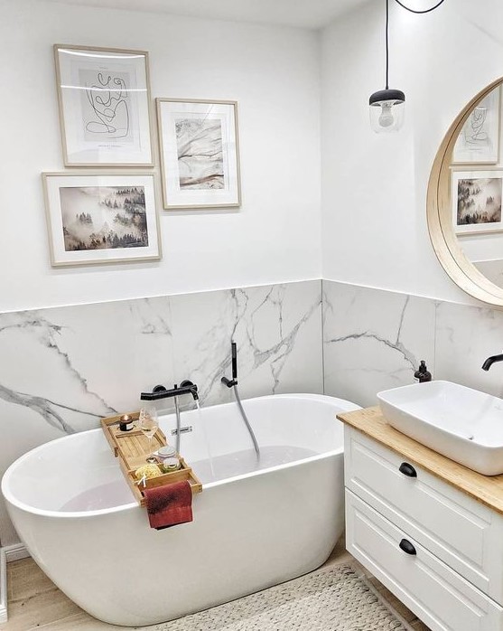 a small contemporary bathroom with a white marble backsplash and white furniture plus a gallery wall