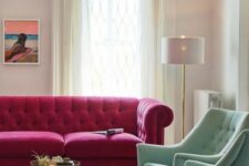 20 a beautiful living room with a magenta sofa, pastel green chairs, a chic chandelier, a bold boho rug, a low table and neutral curtains