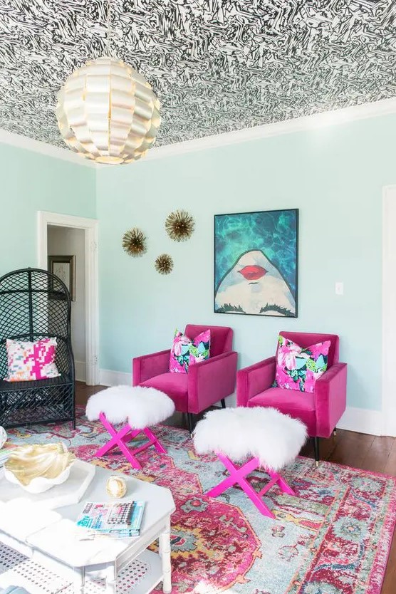 a bold and whimsical living room with a patterned ceiling, magenta chairs and stools, a bold printed artwork and a bold printed rug