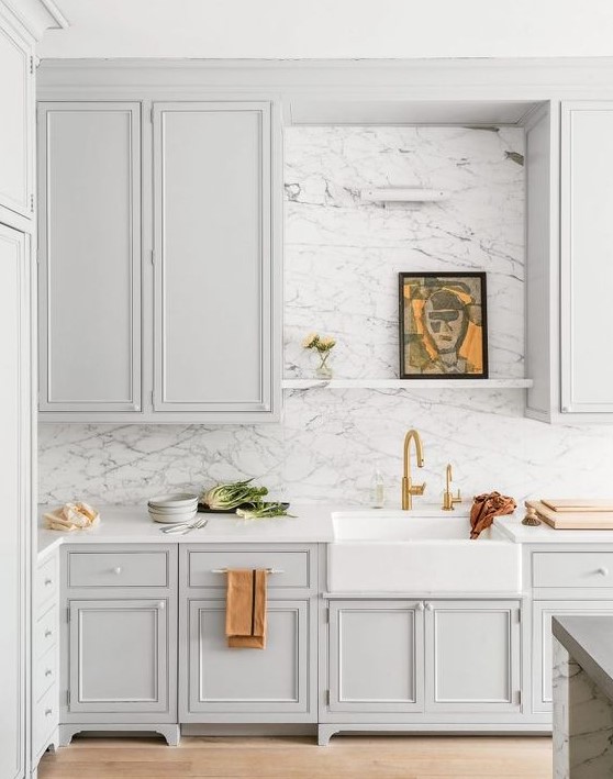 a dove grey farmhouse kitchen with white stone countertops and a white marble backsplash for more elegance