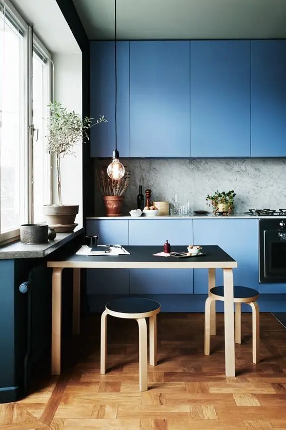 a blue minimalist kitchen with a grey marble backsplash and a black dining set for a gorgeous look