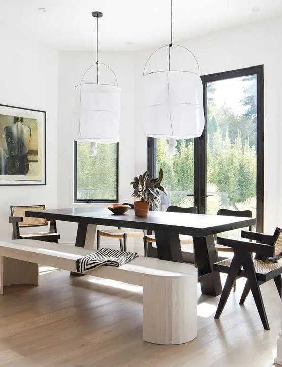 a bold dining zone with a view, a black dining table and chairs, a whitewashed bench and a light-stained floor